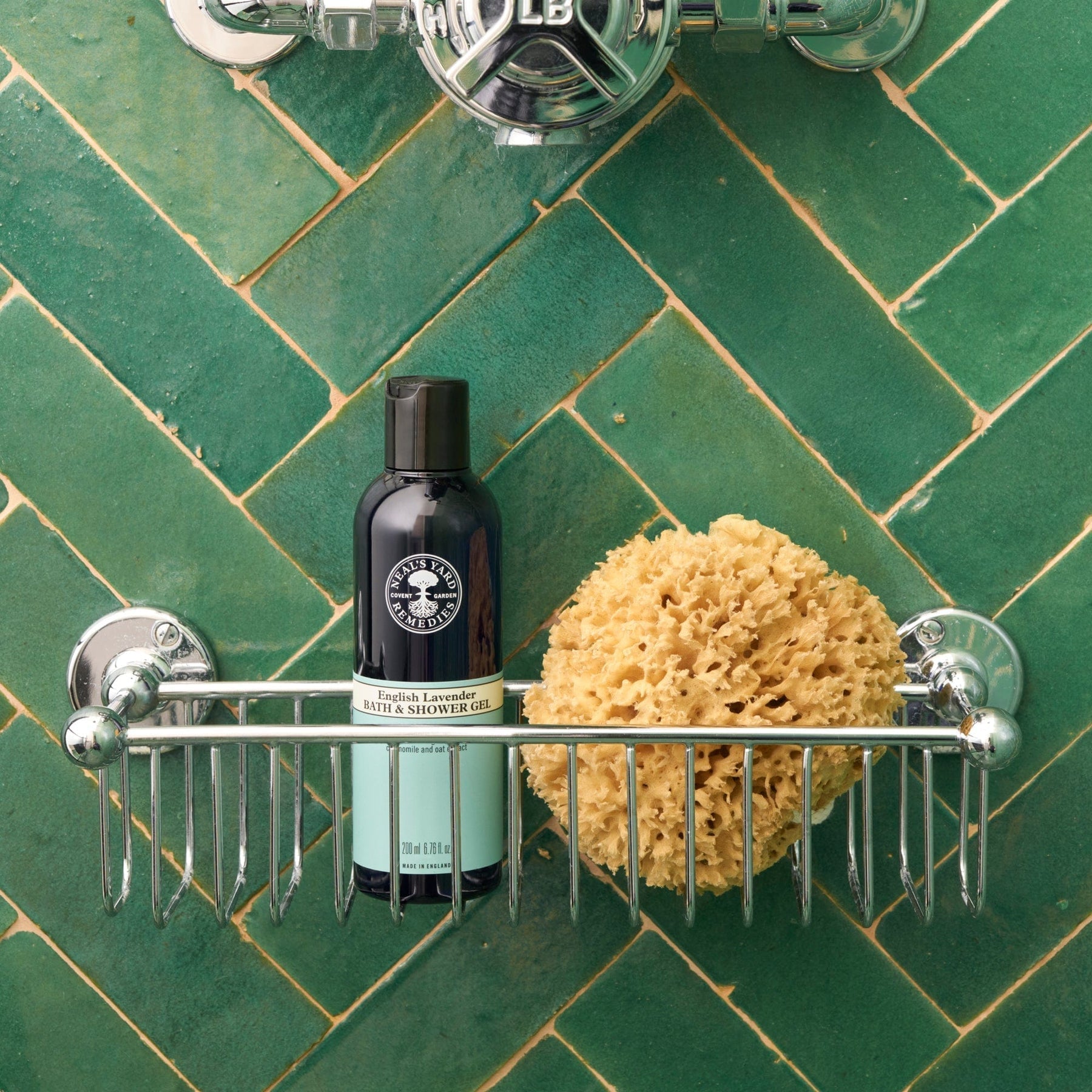 Neal's Yard Remedies English Lavender Bath and Shower Gel on a shower rack with a green tile.